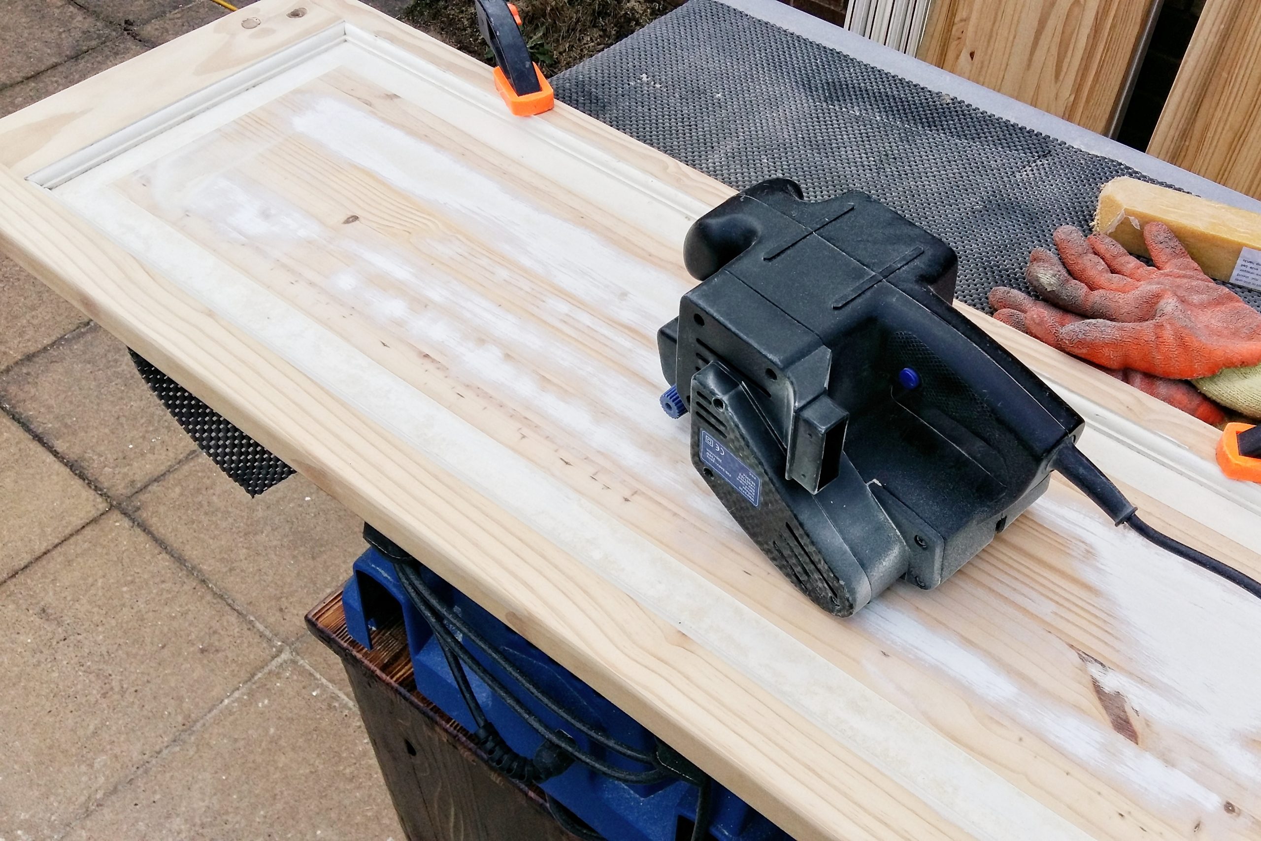 A cheap belt sander removing paint from a door.