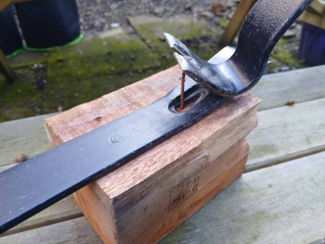 Using two flat pry bars to remove nails from a pallet block.