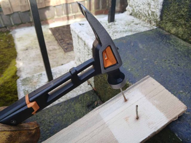 Using a hammer to hit the nails through the pallet planks.