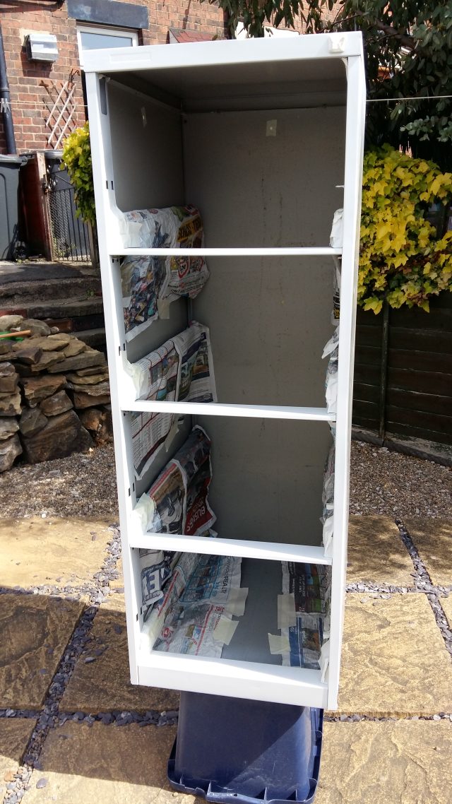 A four-drawer filing cabinet frame, covered in a light grey undercoat of paint.