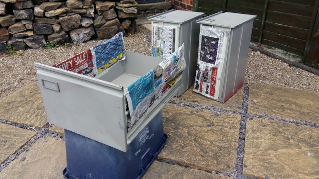 An image of the drawers of a filing cabinet, shown outside on flagstones.