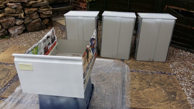 An image of four filing cabinet drawers, with the fronts spray painted white.