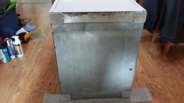 An image of the underside of a filing cabinet, with four squares of carpet glued to each corner.