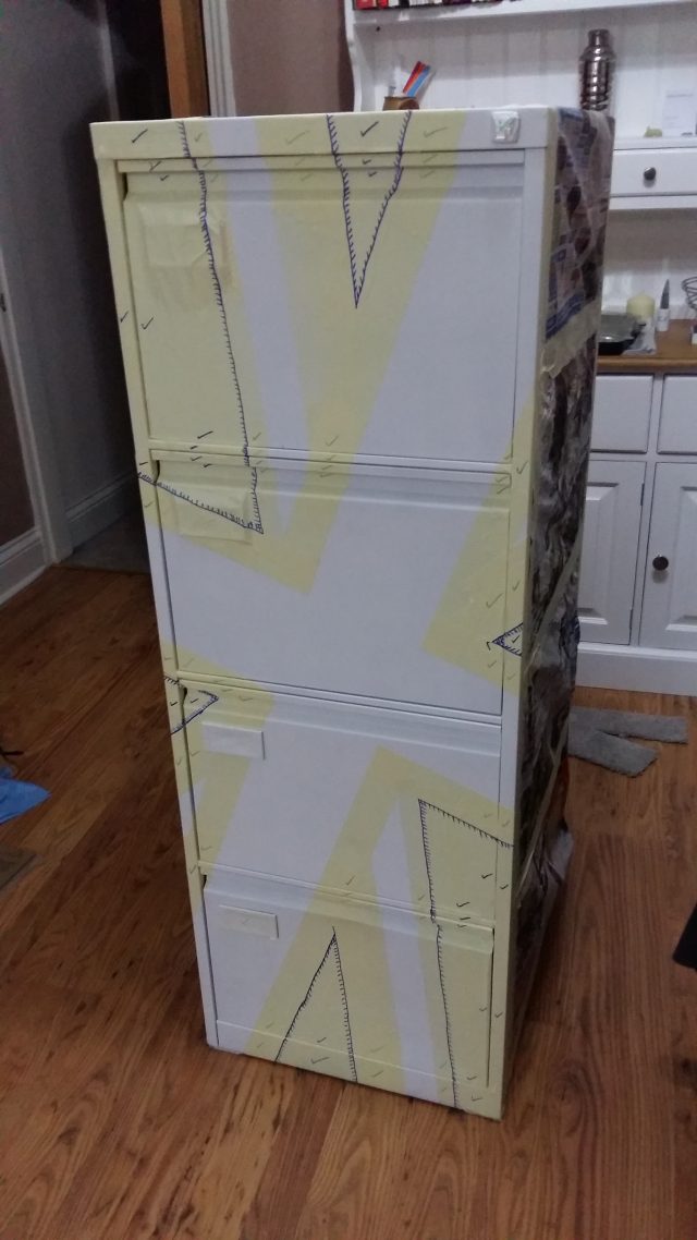 An image of a white, four-drawer filing cabinet, with masking tape on the front.