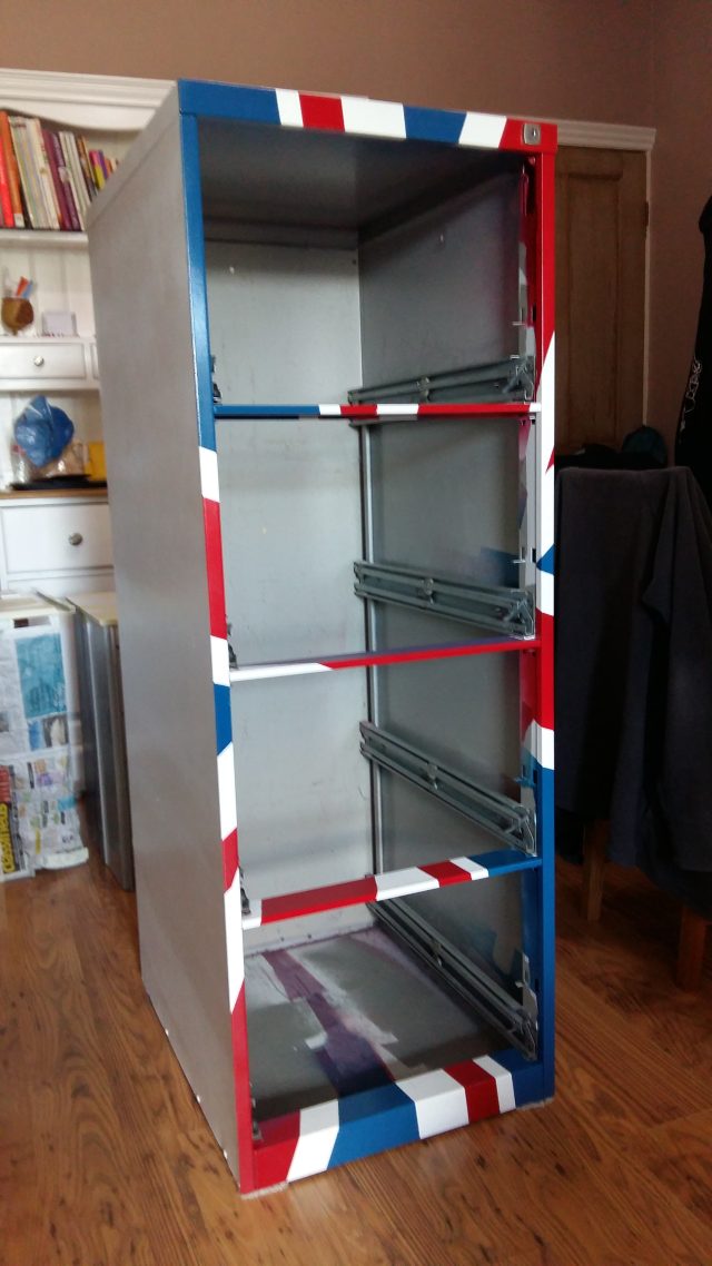 An image of a four-drawer filing cabinet frame, painted in red, white and blue.