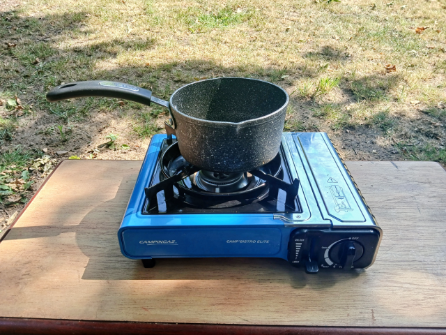 Image of a small gas-powered camping stove, with a saucepan on top.