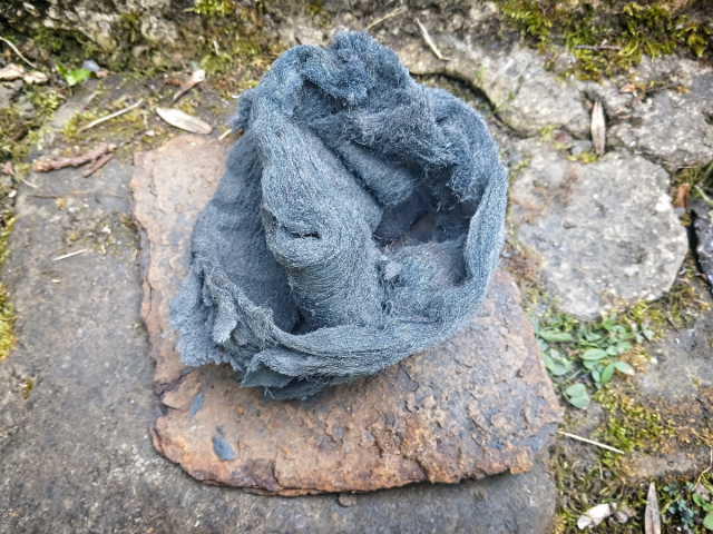 Image show steel wool on a square of rusted metal.