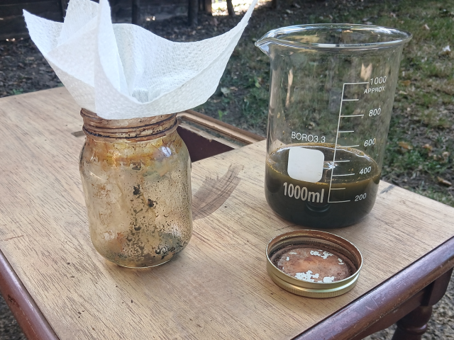 Image shows an empty jar with a piece of paper towel in the opening, next to a 1 litre borosilicate beaker, containing a brown liquid.