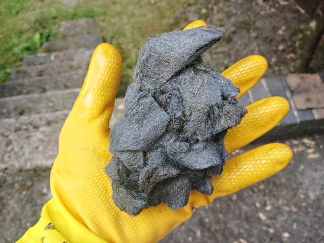 Image shows 0000 grade steel wool in a yellow gloved hand.