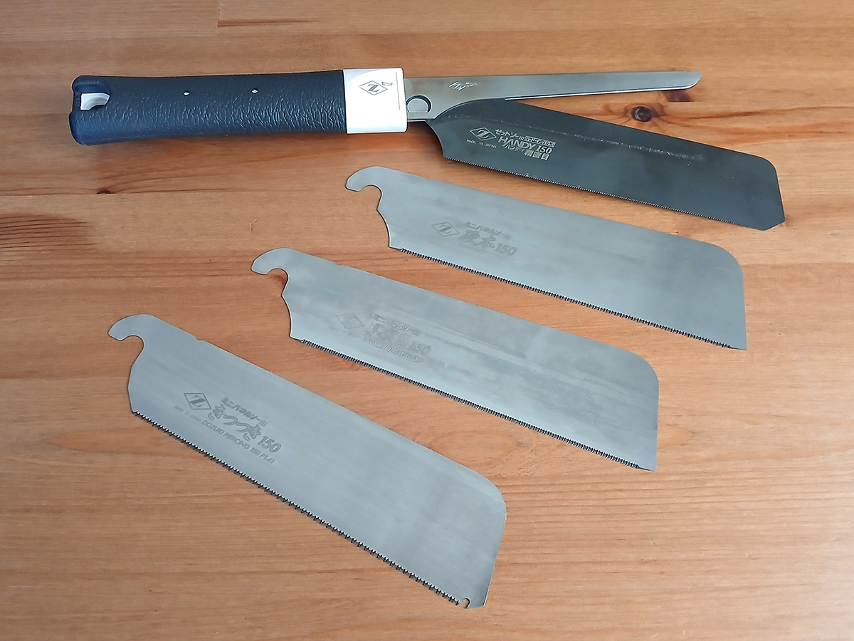 ZETSAW Replacement Blades - Top Image Image shows a Dozuki saw with a black handle and four ZETSAW replacement blades, arranged below it.
