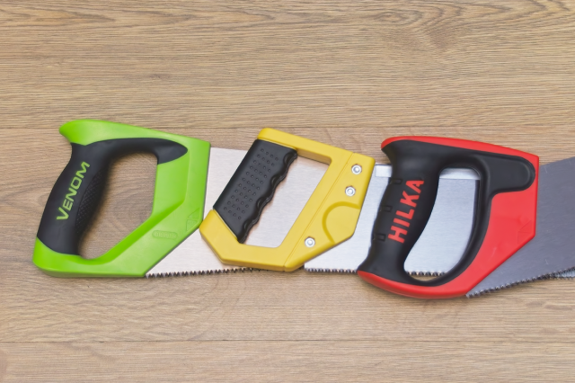 Image shows three D-Handles of Western Saws. One green, one yellow and one red. Shown on a wooden background.