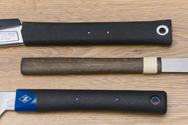 Three straight Japanese saw handles. Shown on a wooden background.
