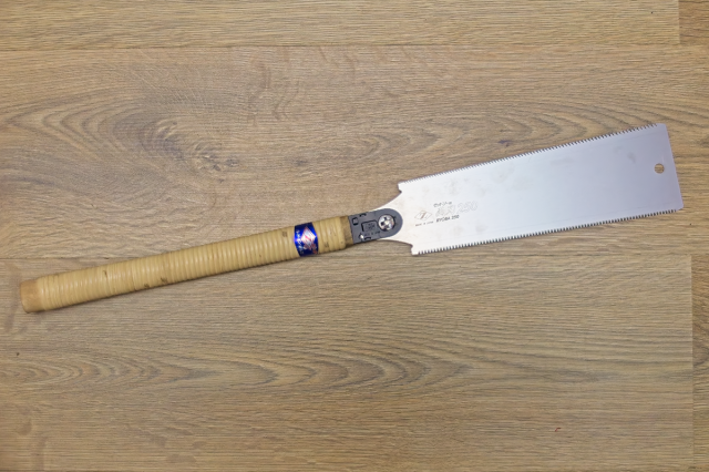 A Ryobo-nokogiri Japanese saw, shown on a wooden background.